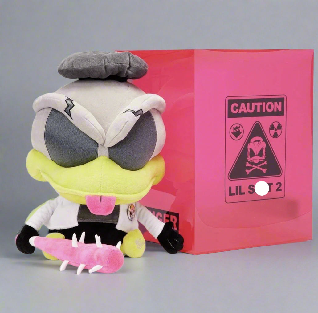 A plush toy with a gray, black, pink, and yellow design, sitting in front of a pink box with 'CAUTION LIL SHIT 2' text.